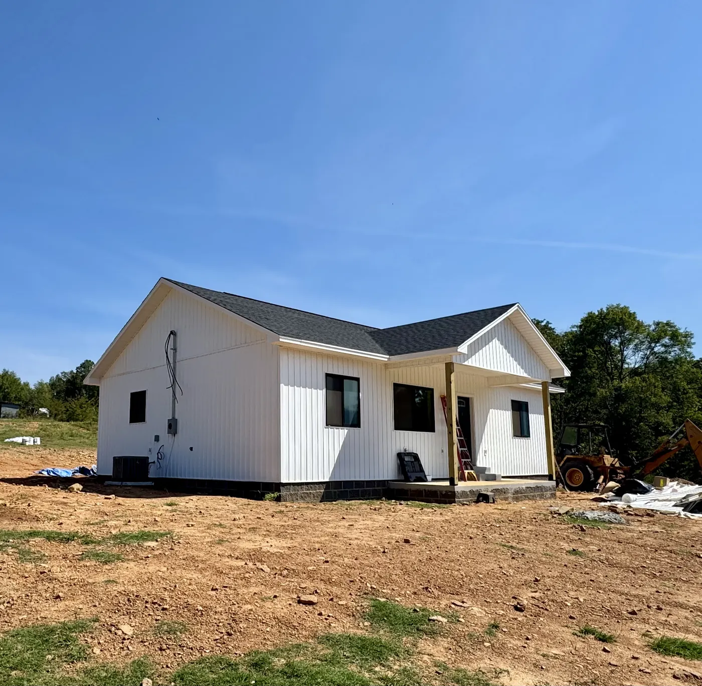 Finished white board-and-batten home with timber porch posts, built from plans