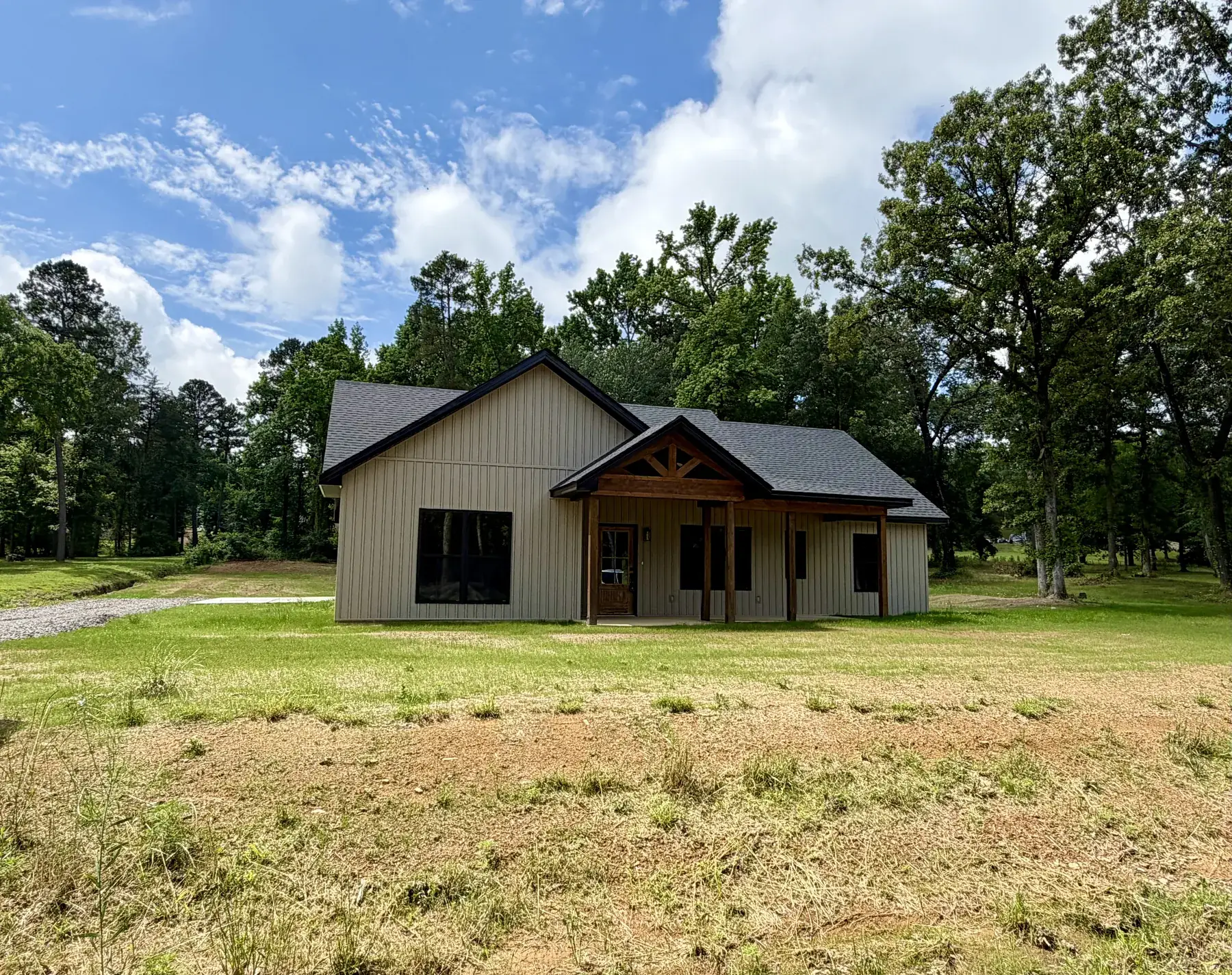 Tan board-and-batten home with a timber-frame gable porch built by C&M Innovations