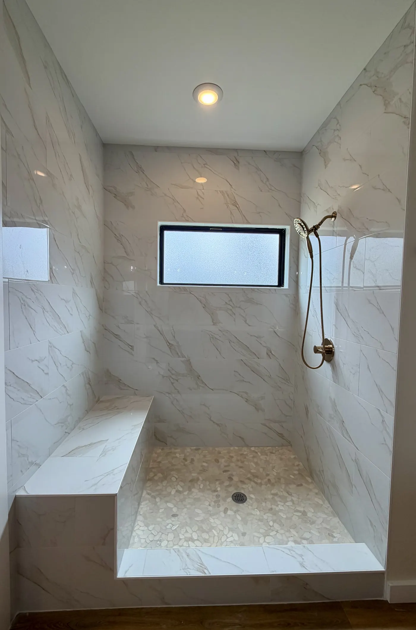 Walk-in tiled shower with bench and marble-look tile