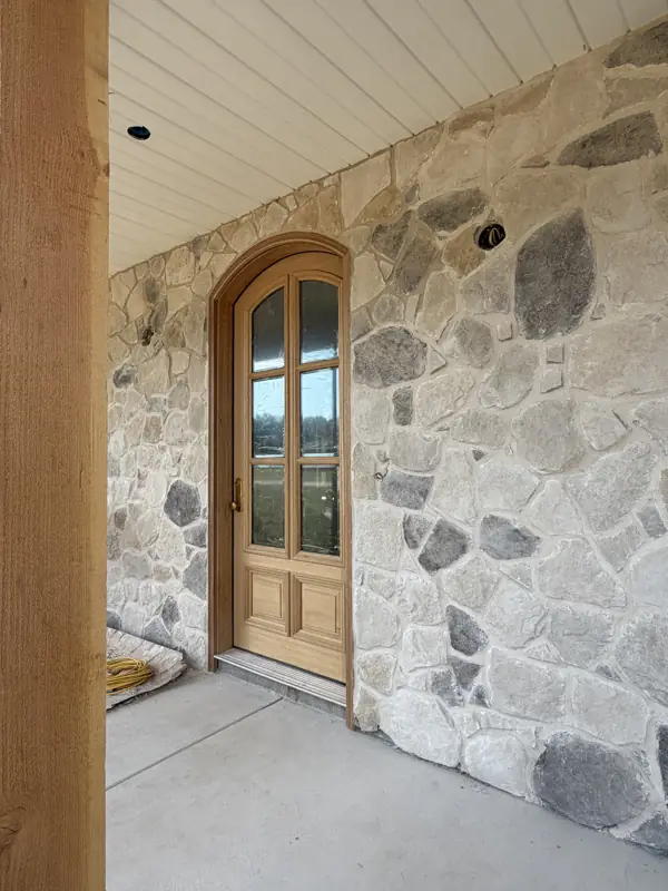 Arched wood front door in a stone entry
